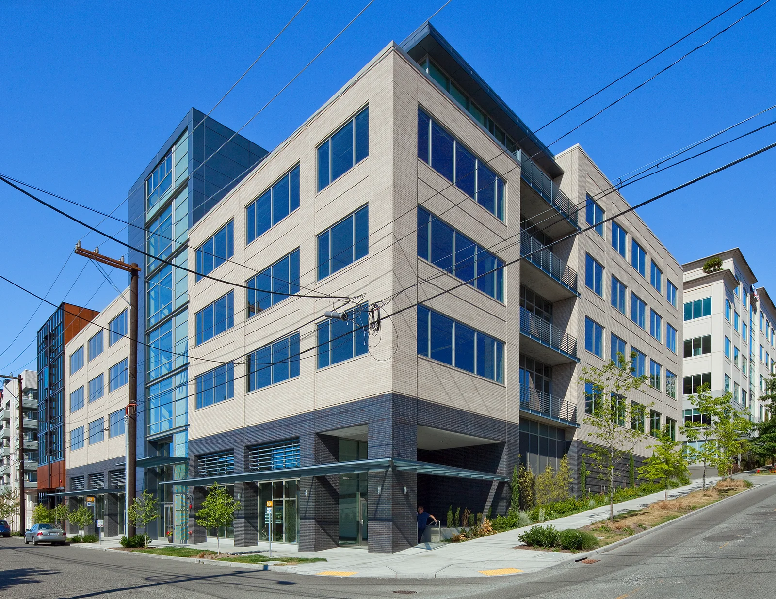 Modern building at 500 Yale Avenue North in Seattle with beige panel facade, balconies, and dark charcoal street-level podium base