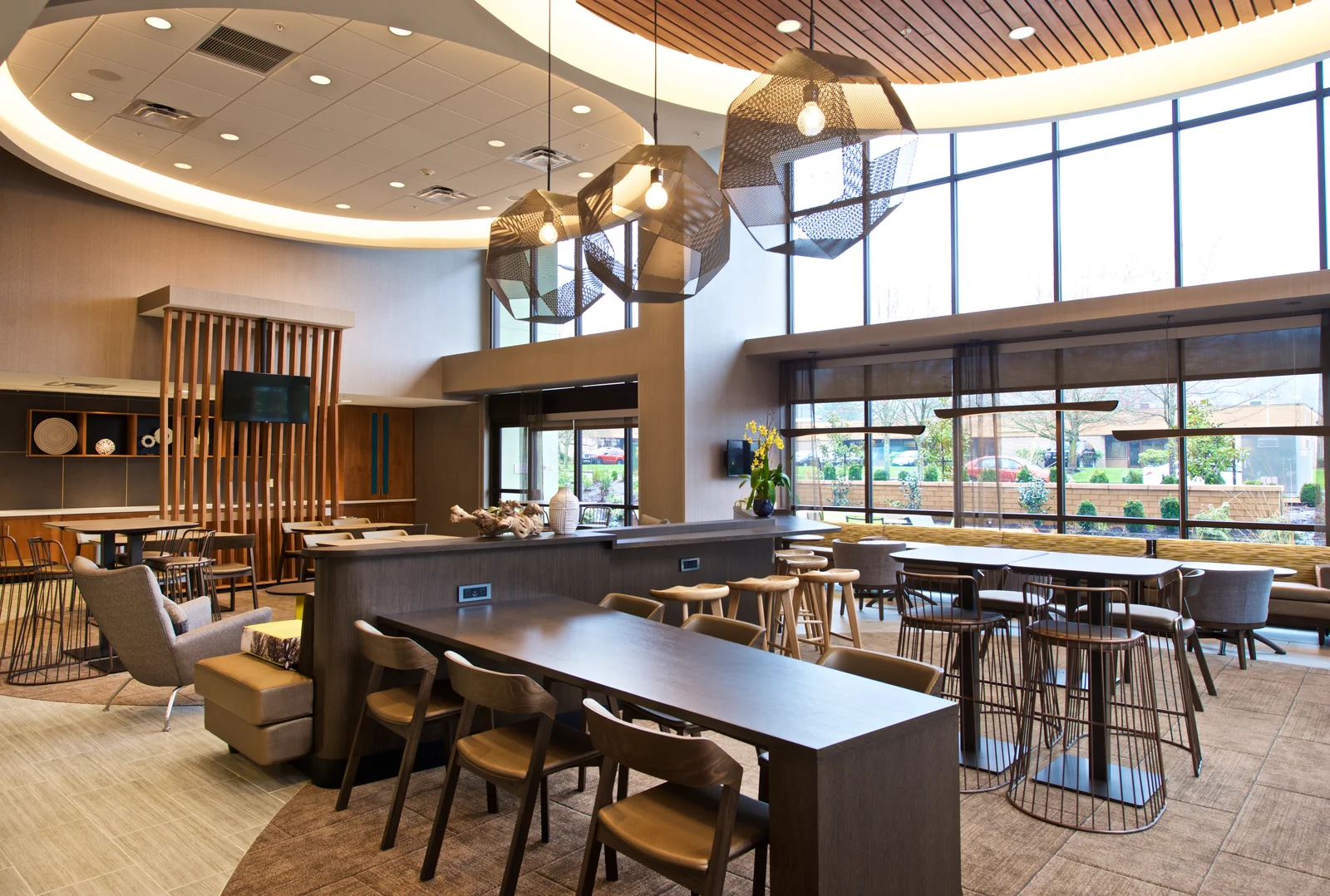 Interior lobby of SpringHill Suites by Marriott hotel at 1185 Northwest Maple Street in Issaquah featuring geometric pendant lights, communal tables, and floor-to-ceiling windows