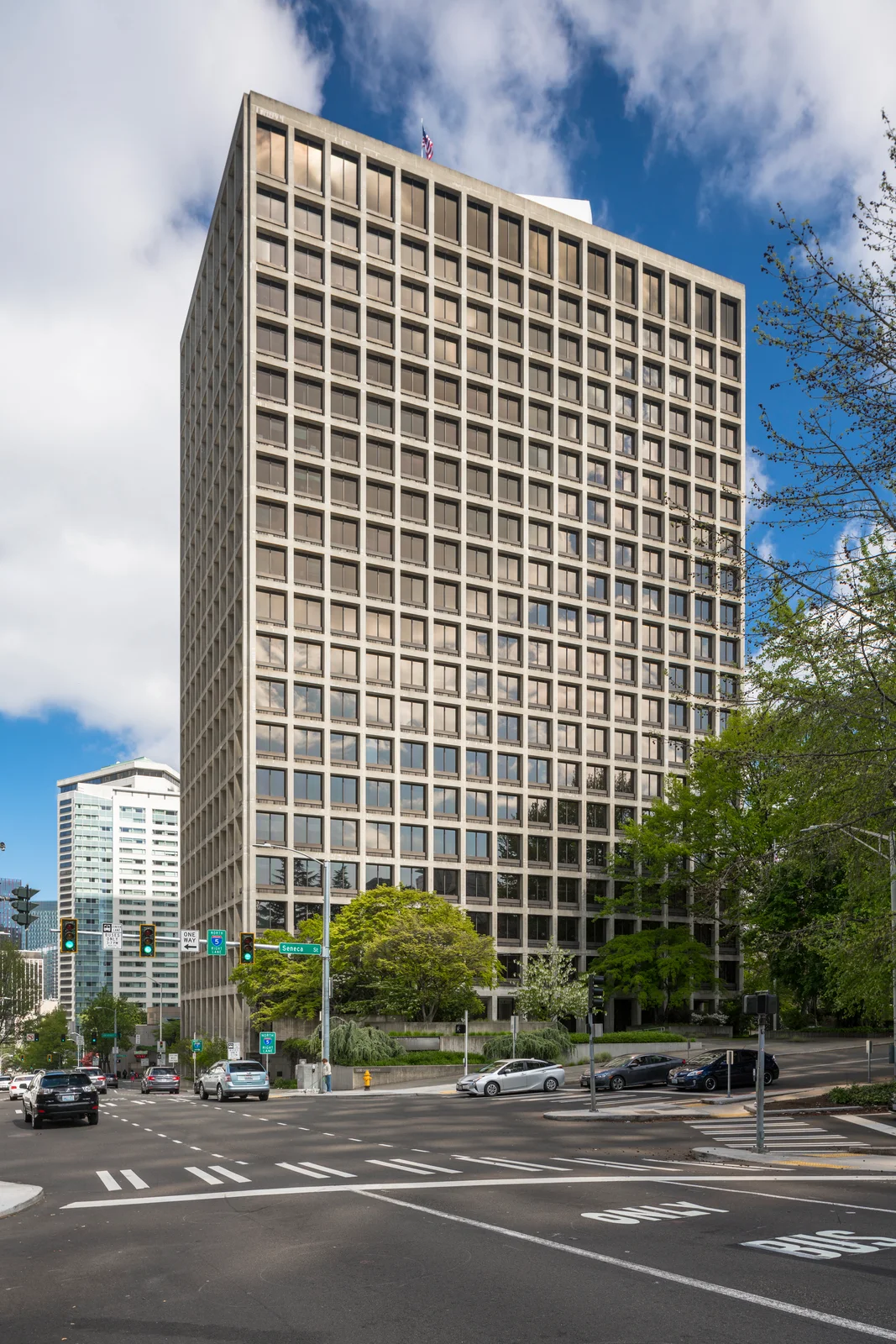Multi-story Park Place modern office tower at 1200 Sixth Avenue in Seattle featuring precast concrete facade and uniform grid of recessed windows with trees in foreground
