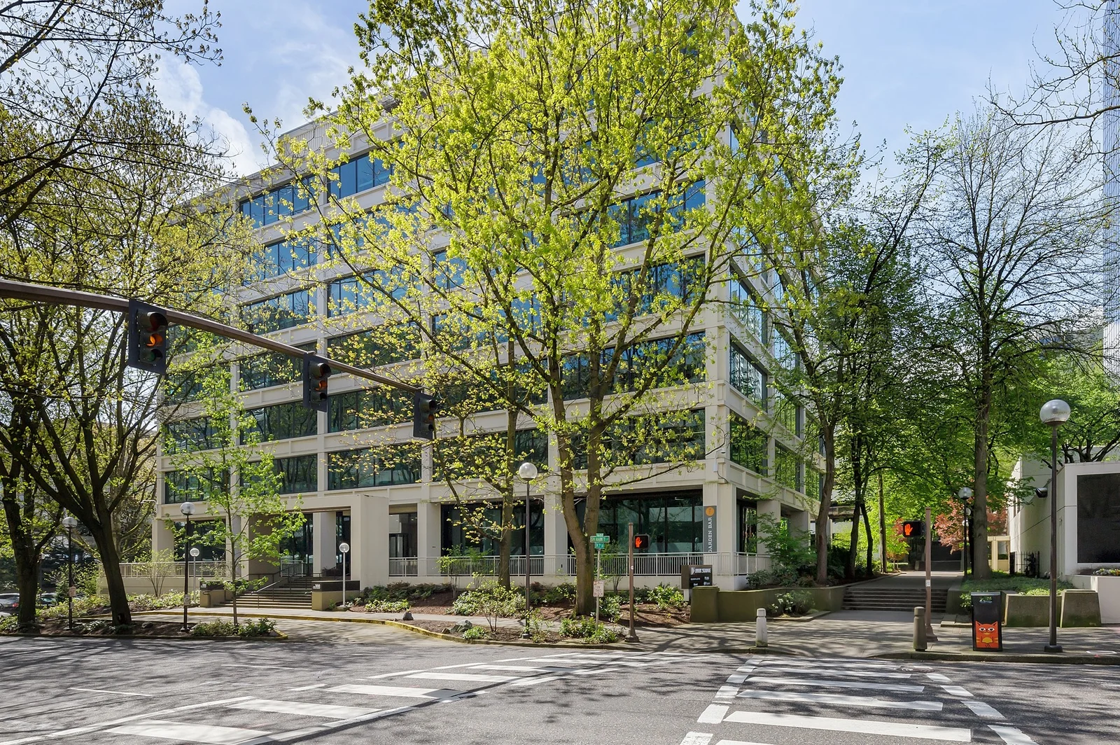 Modern office building at 100 SW Market Street in Portland with glass windows and concrete frame surrounded by trees
